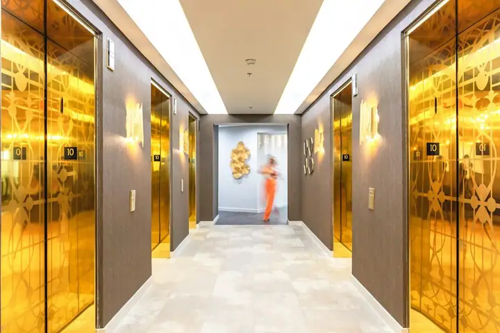 Hallway with gold elevators and blurred figure