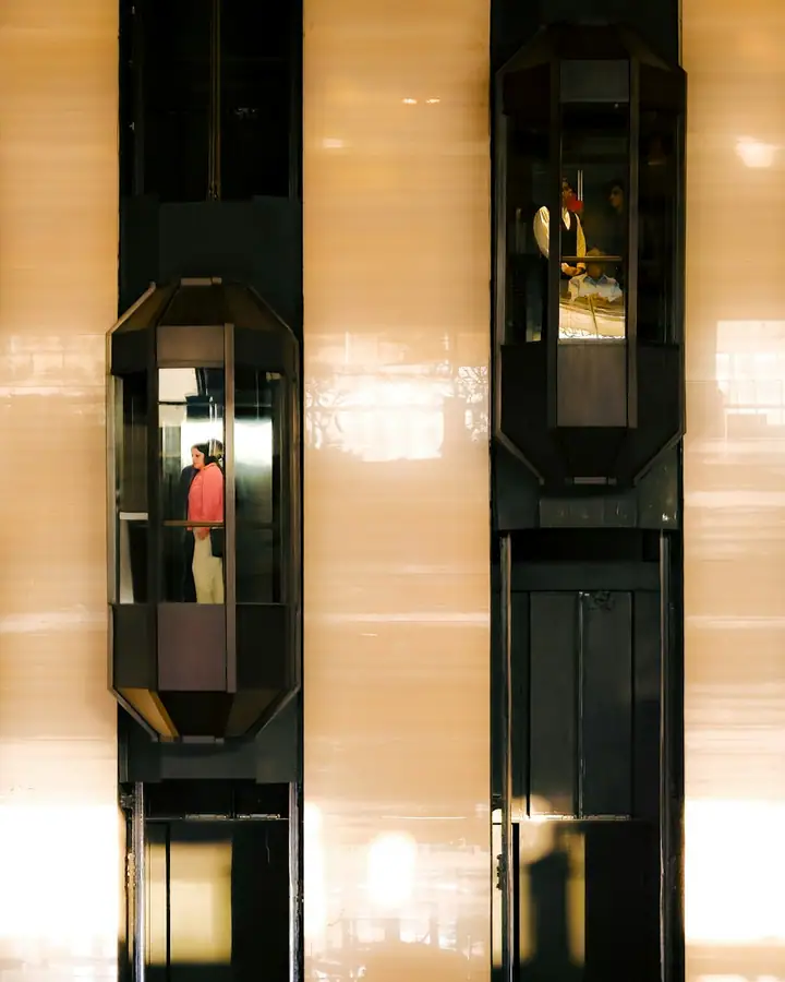 Two elevators are moving up and down a building